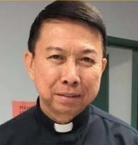 Portrait of a smiling man in a clerical collar, likely a priest.